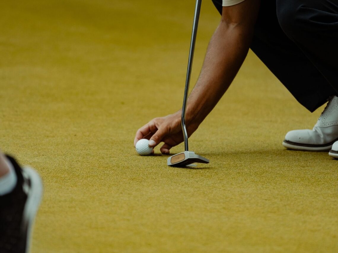 Golfeur alignant une balle sur le green avant un putt