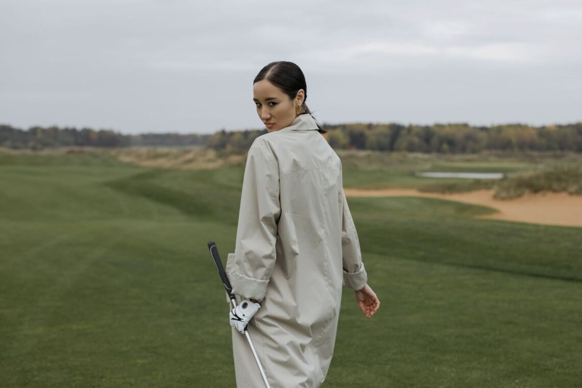 Golfeuse en coupe-vent tenant un club sur un parcours balayé par le vent