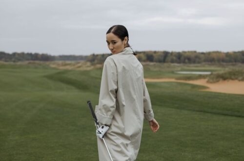 Golfeuse en coupe-vent tenant un club sur un parcours balayé par le vent