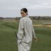 Golfeuse en coupe-vent tenant un club sur un parcours balayé par le vent